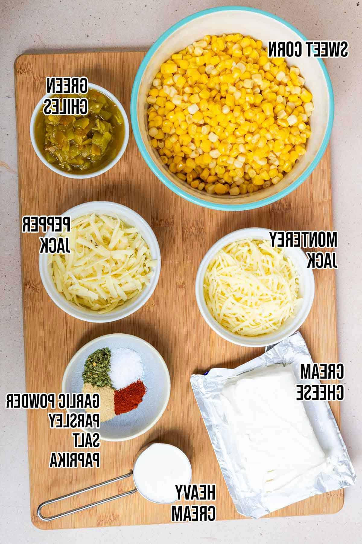 Creamy green chile corn casserole ingredients: cream cheese, heavy cream, green chile peppers, sweet corn, pepper jack cheese, monterey jack cheese, garlic powder, dried parsley, salt, and paprika.
