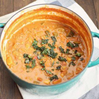 overhead photo of a pot of bean and beef stew topped with herbs on a white and blue towel