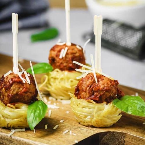 Spaghetti nests appetizer with meatballs with toothpicks.