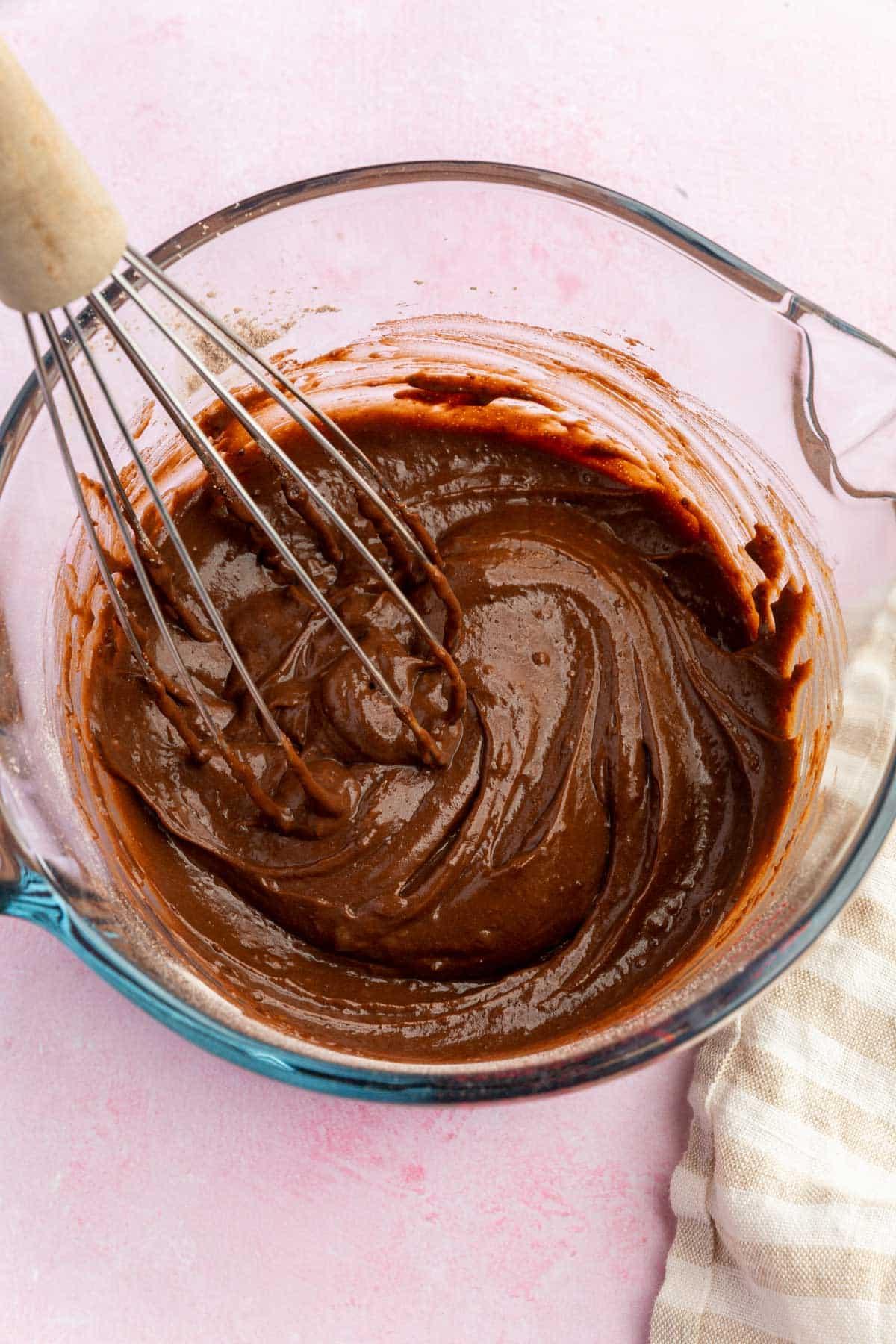 Chocolate pudding in a measuring glass with a whisk.