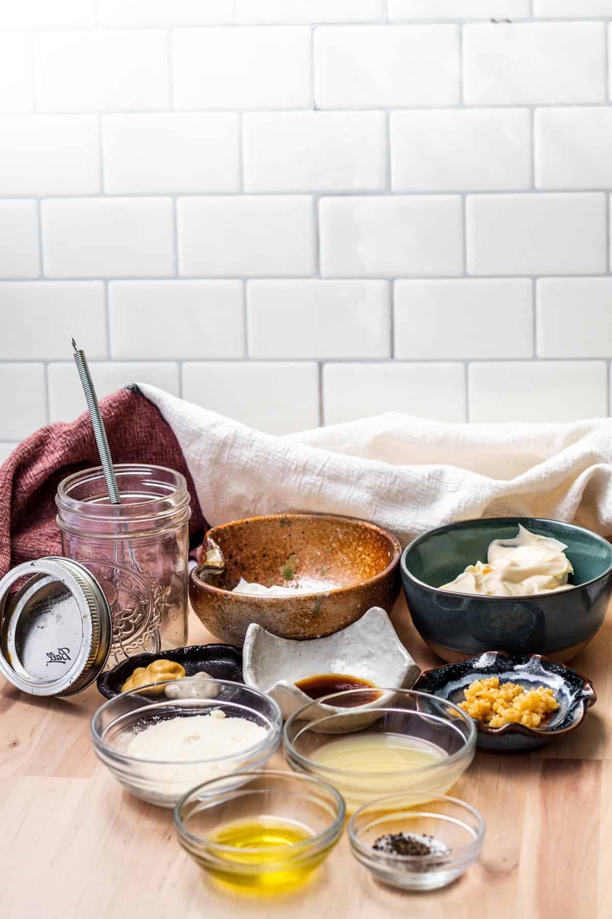 Dressing ingredients laid out on wooden table in small glass bowls.