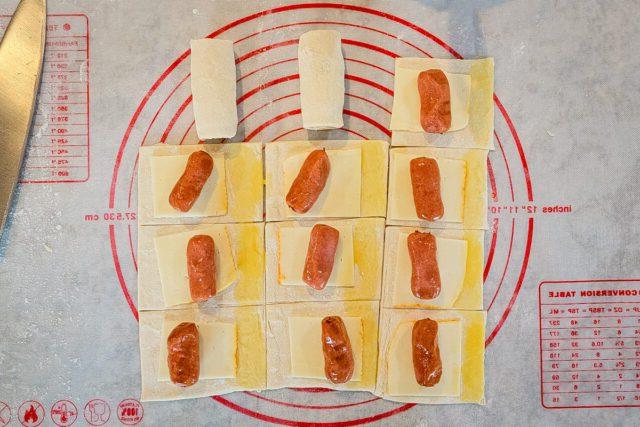 Place a little smokie on each piece of pastry and brush some of the egg wash on the edge of each square.