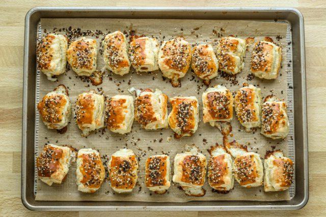 Baked puff pastry pigs in a blanket on the baking sheet.