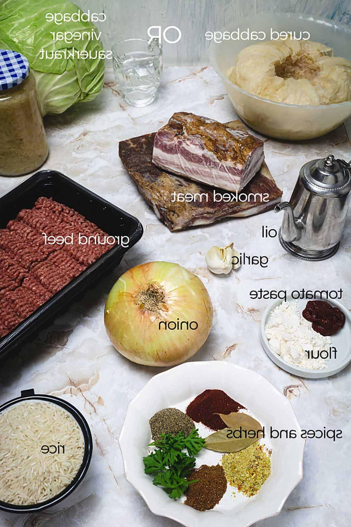Ingredients for making stuffed cabbage rolls on a table with meat, cabbage, rice, vegetables, spices, and seasonings..