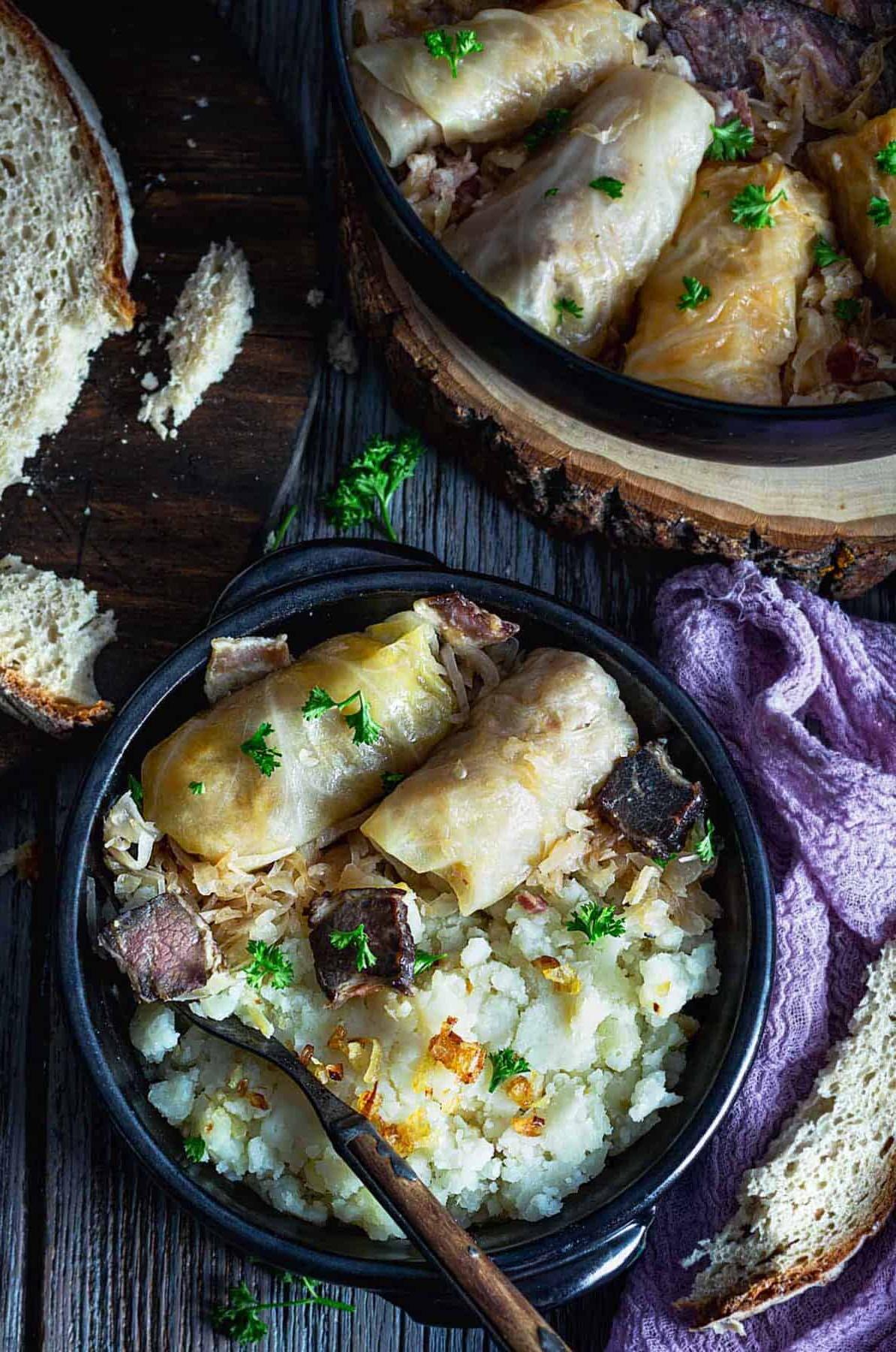 An overhead view of two cabbage rolls on a plate with mashed potatoes and a spoon.