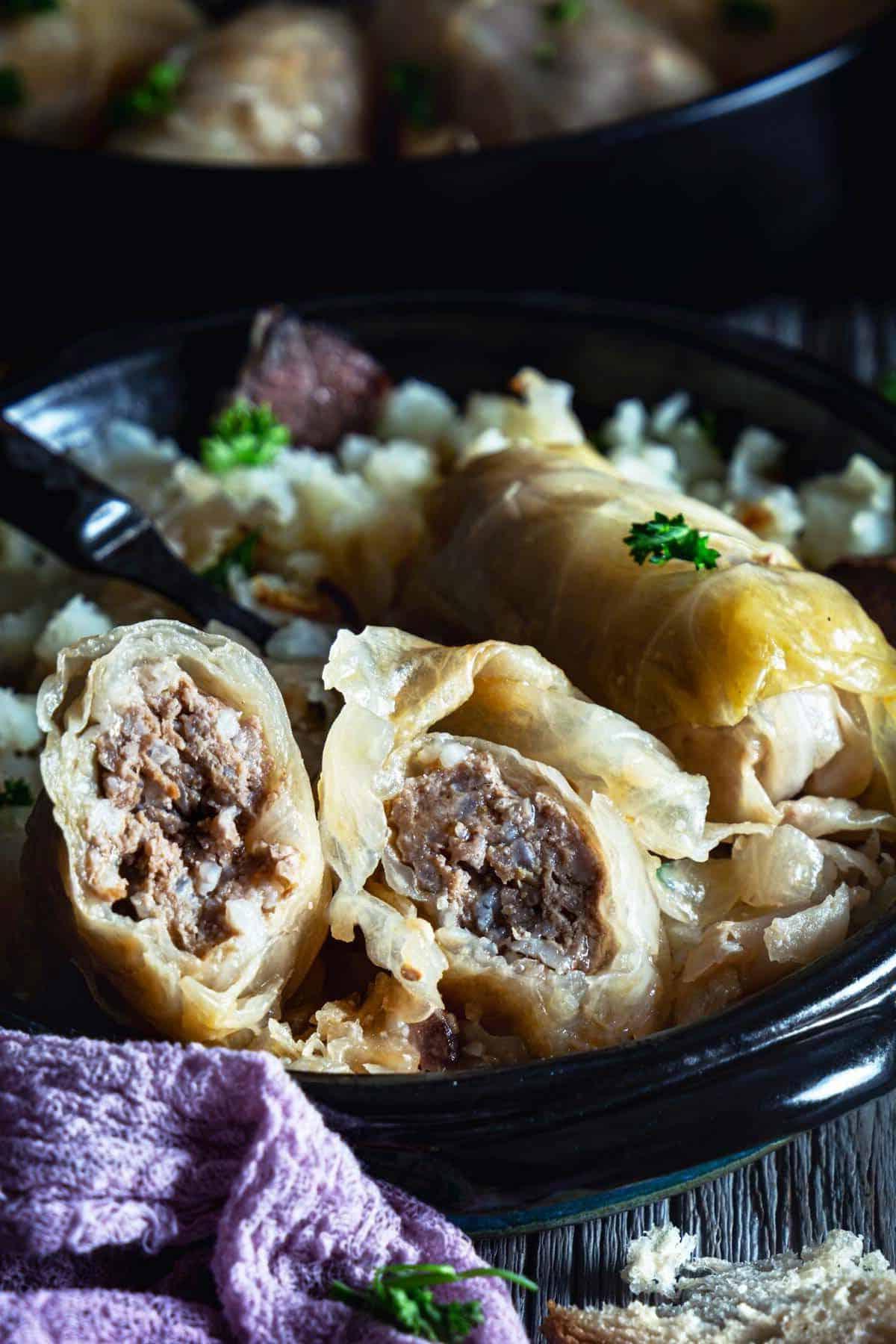 A close up of the cabbage roll cut in half showing the ground beef filling inside.